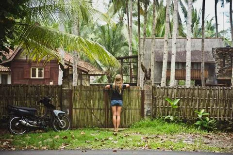 Indonesia, Java, back view of woman leaning on garden gate looking at houses Fotos de archivo