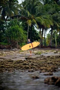 Indonesia, Java, man carrying surfboard at the coast Stock Photos