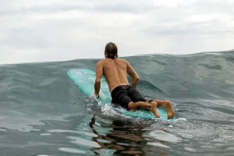 Indonesia, Java, man lying on surfboard on the sea Stock Photos