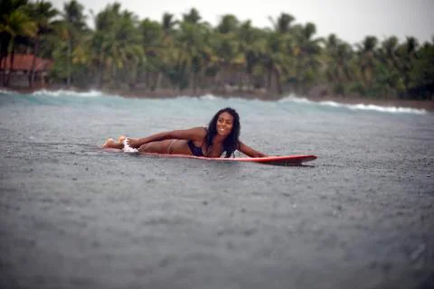 Indonesia, Java, woman lying on surfboard on the sea in rain Photos