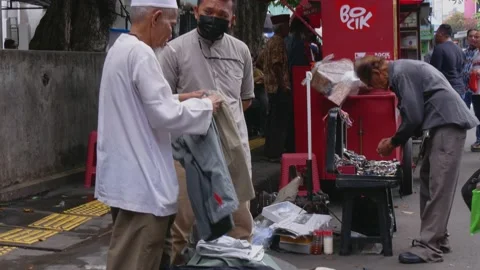 Indonesian clothes vendor serving customer at a bazaar on the side of the street Stock Footage 237814529