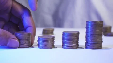 Indonesian coins stack on the table. A man hand's adds gold coins to a stack Stock Footage 287741555