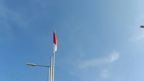 Indonesian flag on a pole fluttering in the wind, against blue sky Stock Footage 212841551