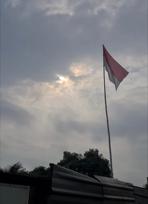 Indonesian flag waves gently under a cloud-covered sunrise Video stock 311494541
