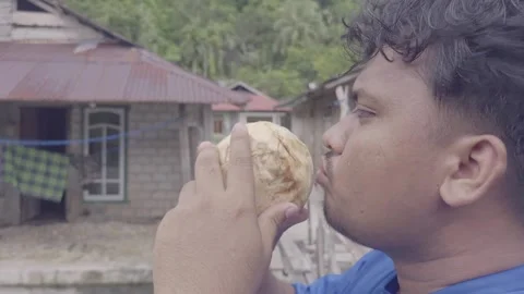 Indonesian man drinking fresh coconut water in village outdoor setting no au Vídeos de archivo 332589987