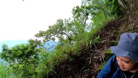 An Indonesian man gets up to continue his hiking trip at mountain trail Stock Footage 279326306