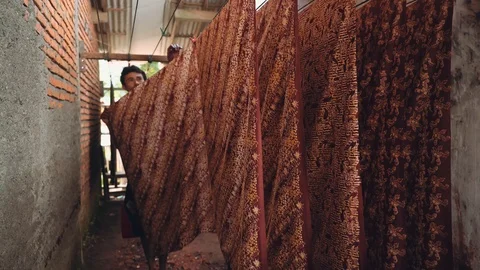 Indonesian man taking dried batik fabric from rope Stock Footage 89032456