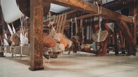 Indonesian man using foot-treadle loom machine with foot Stock Footage 90707525