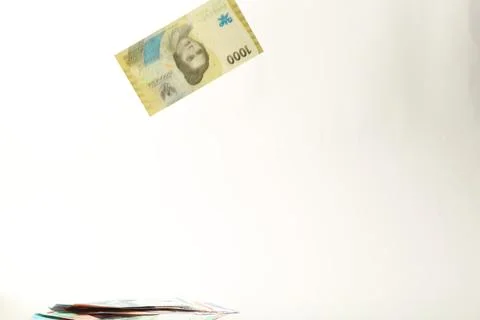 Indonesian Rupiah Banknote Falling with Stack Below on White Background Stock Photos