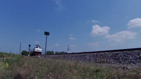 Indonesian Train Passing in Medium Speed Under Bright Blue Sky Sunny Day Stock Footage 209450427