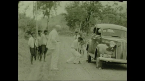 Indonesians fixing white man's flat tire, Indonesia 1920's. Stock Footage 92413291