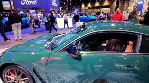 The indoor auto show, filled with visitors walking through brightly li Stock Footage 306435527