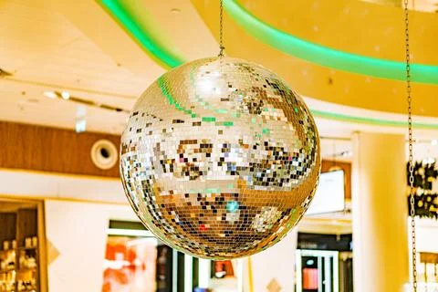 Indoor disco scene featuring a large, shiny disco ball reflecting colored l.. Stock Photos