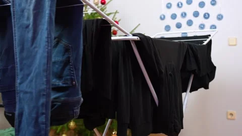 Indoor drying rack with jeans and black clothes in a small living room Vídeos de archivo 325842932