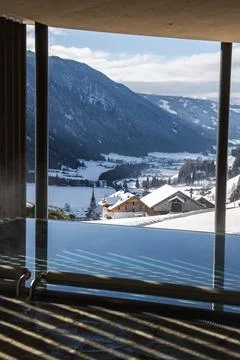 Indoor infinity pool facing Dolomites valley with chalets and church Stock Photos