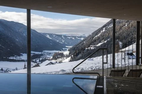 Indoor infinity pool overlooking snowy Dolomites valley in Italy Stock Photos