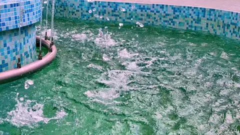 Indoor pool with curved tiled edge and blue mosaic walls, turquoise water jets Video stock 343628794