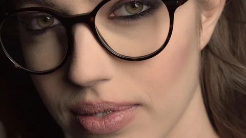 Indoor portrait of young good-looking girl in round glasses with braces on gray Stock Footage 86236489
