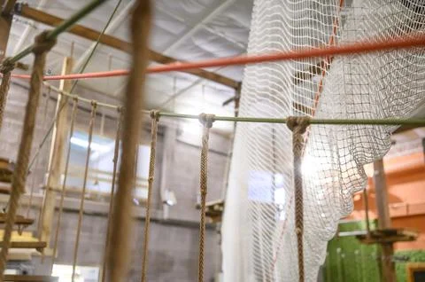 Indoor ropes course with climbing elements and safety netting visible Stock Photos