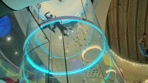 Indoor skydiving instructor training participant in vertical wind tunnel at Stock Footage 307782097