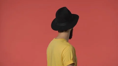 Indoor video man in black hat, yellow t-shirt standing backwards, turn camera Stock-Footage 115777978