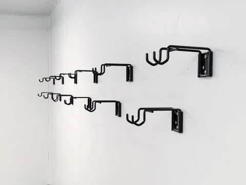 An indoor view showing multiple empty black metal bicycle storage hooks and m Stock-Fotos