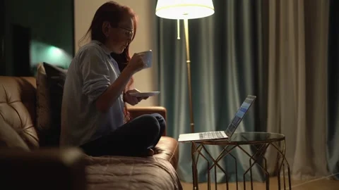 Indulging in a Cozy Evening at Home while enjoying my Laptop and sipping on a Video stock 289966295