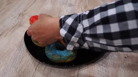 Indulging in vibrant donuts adorned with blue and red toppings, beautifully pres Stock Footage 344093736