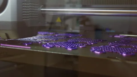 Industrial 3D printer producing glowing purple plastic parts on build platform Stock Footage 346558784