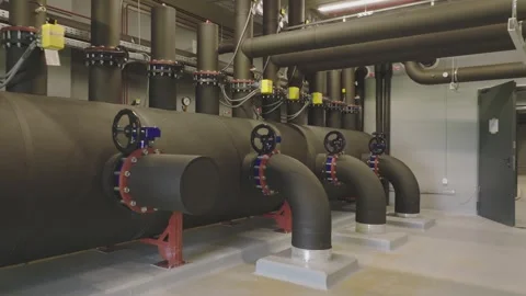 Industrial basement heating system with black insulated pipes and valves in.. Stock Footage 337523220