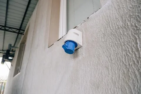Industrial blue electrical power socket mounted on an textured exterior build Stock Photos