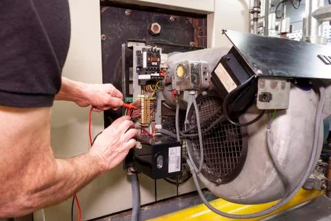 Industrial boiler engineer using a tester to check wiring Foto stock