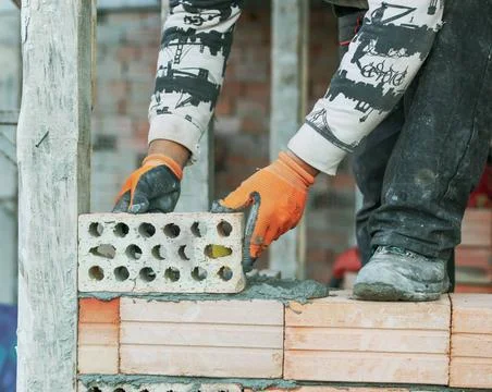 Industrial bricklayer installing bricks on construction site Industrial br... Stock Photos