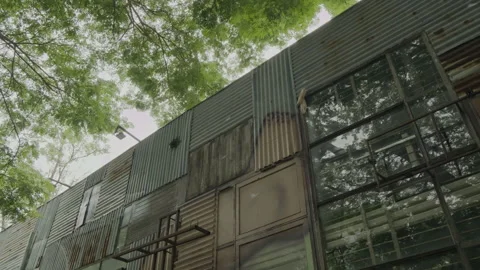 Industrial building facade beneath tree canopy in slow motion Vídeo Stock 337384668