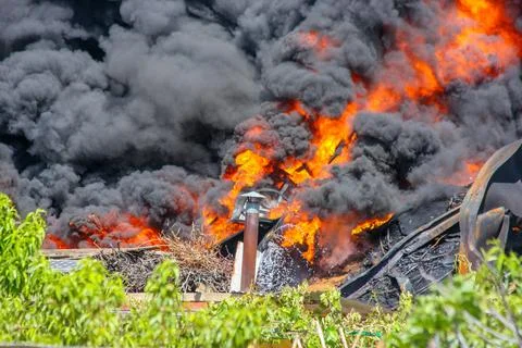 Industrial building fire creating thick black smoke pollution Stock Photos