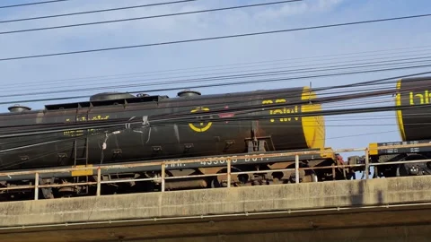 Industrial cargo train transporting freight on elevated tracks with power lines Vídeos de archivo 339097797