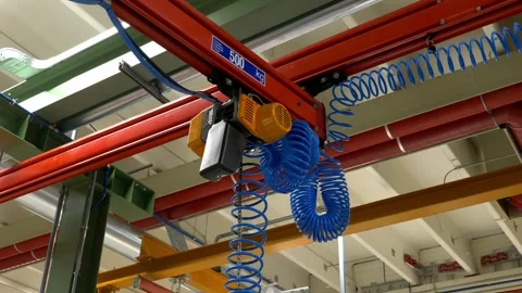 Industrial ceiling crane system with blue air hoses in a modern workshop Stock Footage 328644901