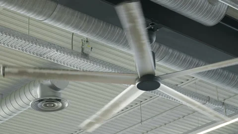 Industrial ceiling fan rotates under metal roof with ventilation duct system Stock Footage 343950479