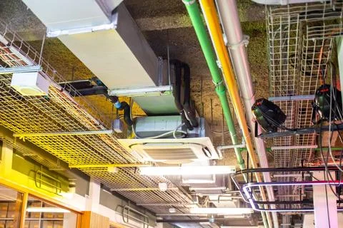 Industrial ceiling utility installation with electrical wire trays, air con.. Stockfoto's