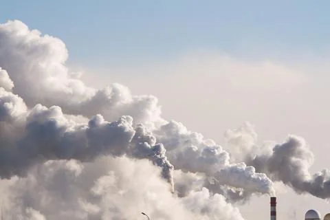 Industrial chimneys with heavy smoke causing air pollution on the blue sky Stock-Fotos