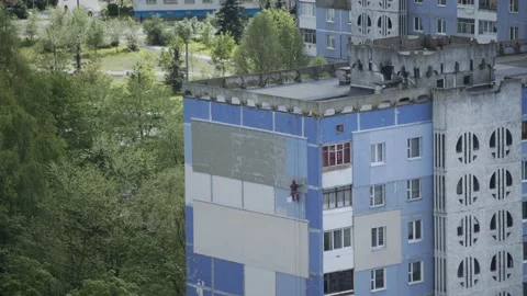 Industrial climber paints insulation of building in blue. Accelerated video. Stock Footage