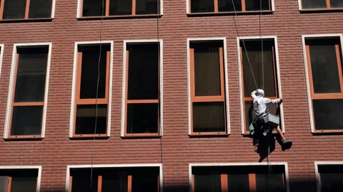 An industrial climber washes windows on the facade of a multi-story building Stock Footage 344470502