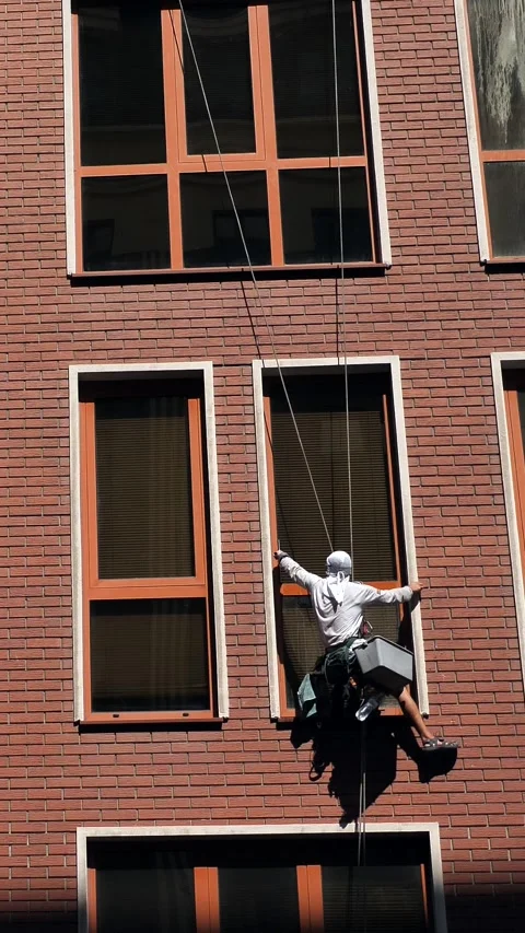 An industrial climber washes windows on the facade of a multi-story building Stock-Footage 344472260