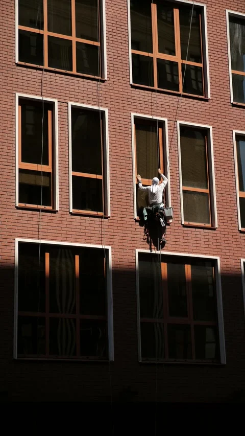An industrial climber washes windows on the facade of a multi-story building Stock Footage 344472411