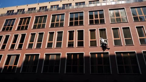 An industrial climber washes windows on the facade of a multi-story building Stock-Footage 344472466