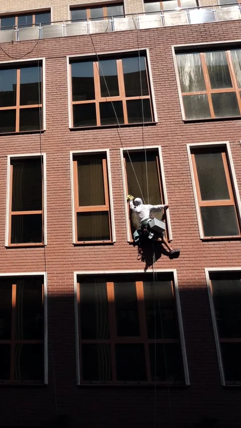An industrial climber washes windows on the facade of a multi-story building Stock Footage 344472503