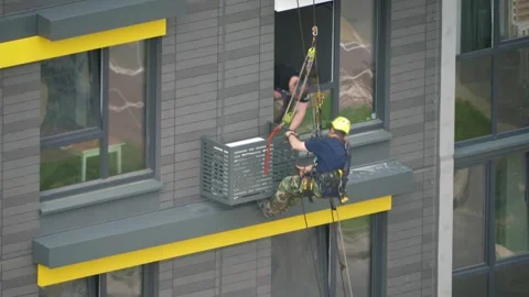 Industrial climber worker installing air conditioner unit on building facade Video stock 320796255