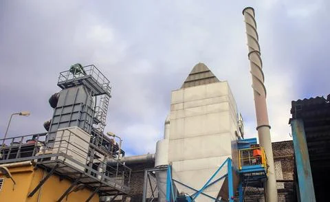 Industrial Complex Against A Cloudy Sky With A Large Exhaust Stack Stock Photos