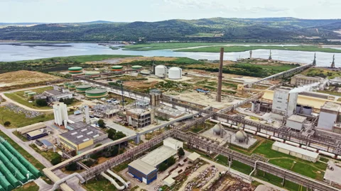 Industrial complex located near water with large storage tanks and pipelines in Stock Footage 341128182