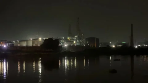 Industrial complex at night with illuminated structures reflecting on a cal.. Stock Footage 340055933